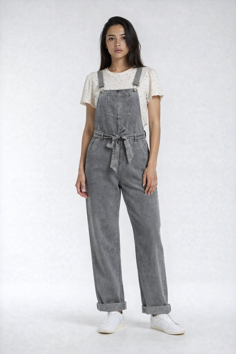 Person wearing gray overalls and white colette shirt on a white background