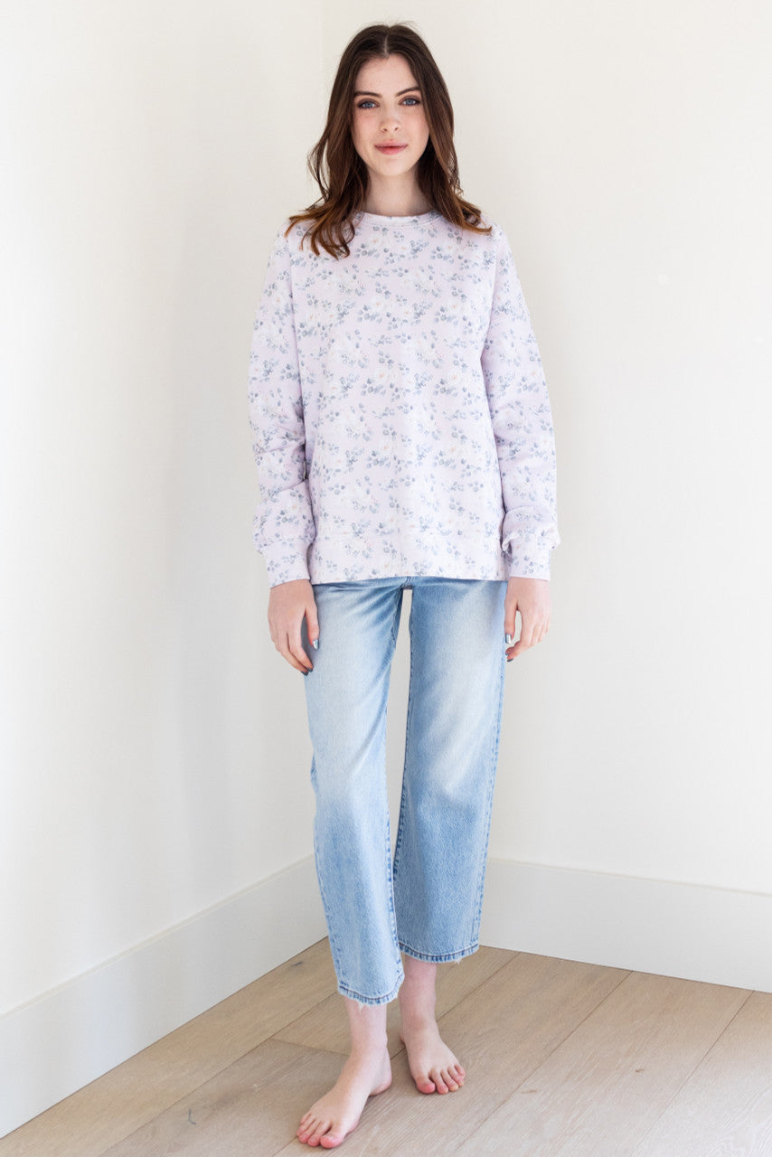 This soft lilac coloured long sleeve crew neck sweater has a white rose print pattern and ribbing details, giving it a stylish and feminine touch. It has a slightly boxy fit, making it comfortable and easy to wear for any casual occasion.