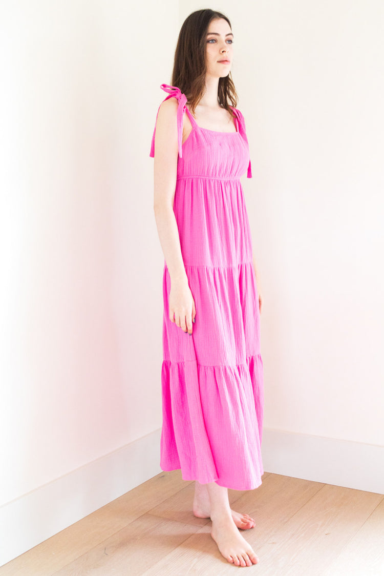 This tie shoulder poplin dress is crafted from a lightweight textured fabric for ultimate comfort. Available in both vivid pink and classic black, it's the perfect choice for casual get-togethers. The tie shoulder detail adds a playful touch to the effortlessly chic silhouette, making it a versatile addition to your summer wardrobe.