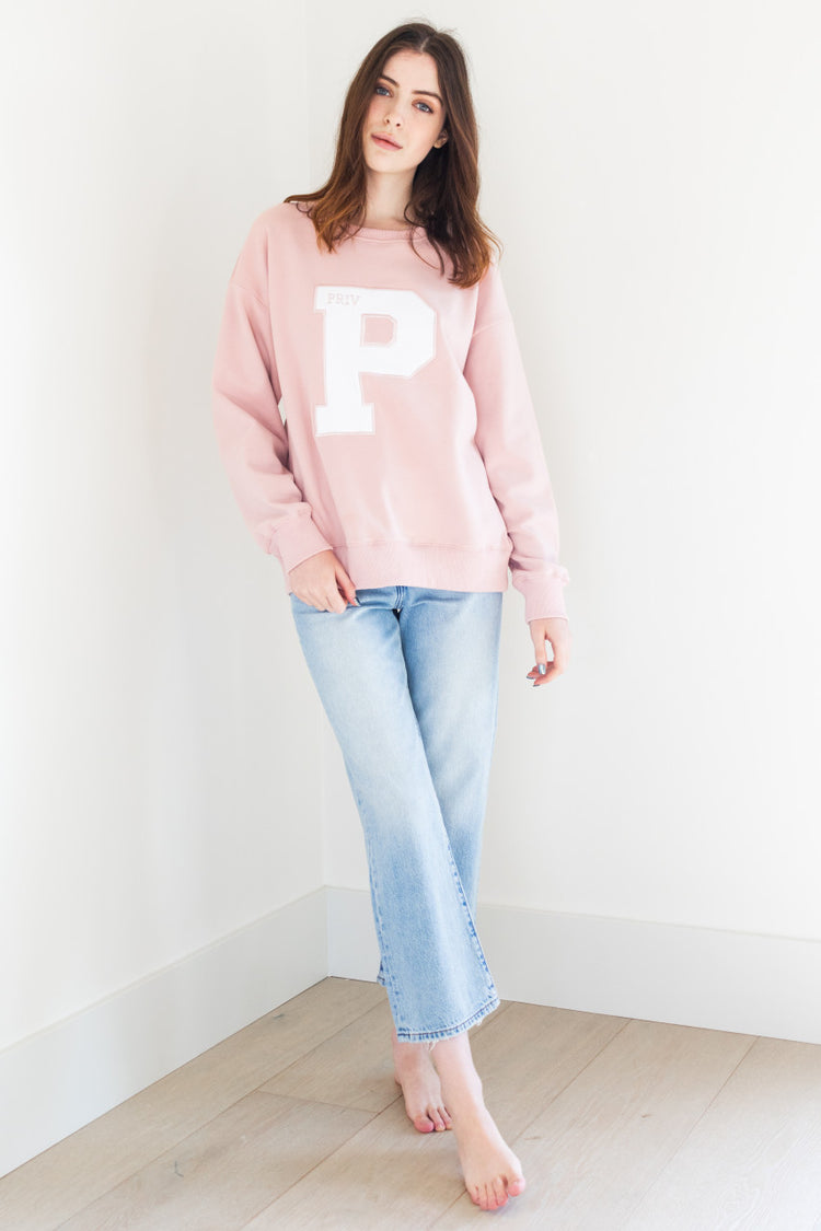 This long sleeve crew neck sweater features a collegiate branded letter P on the front and has ribbing details for added style. It comes in both white and pink, and is made of a soft and comfortable fabric perfect for any casual occasion.

