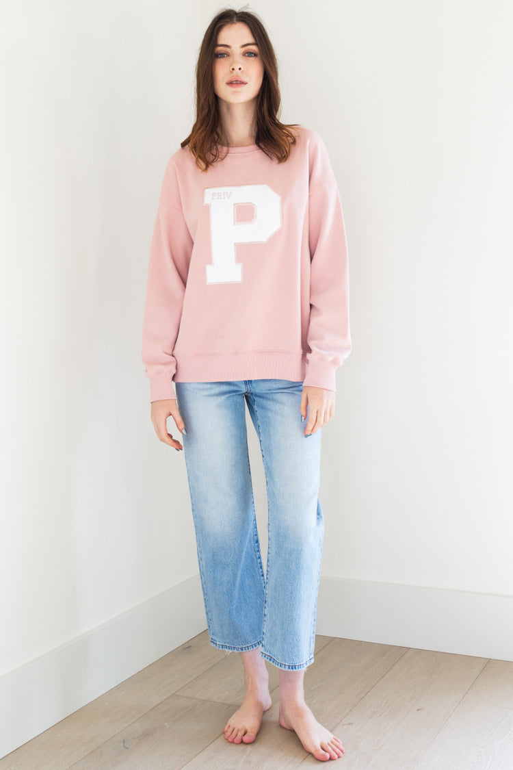 This long sleeve crew neck sweater features a collegiate branded letter P on the front and has ribbing details for added style. It comes in both white and pink, and is made of a soft and comfortable fabric perfect for any casual occasion.


