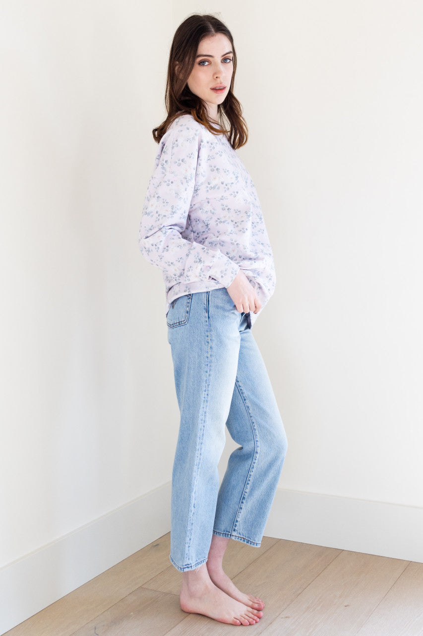 This soft lilac coloured long sleeve crew neck sweater has a white rose print pattern and ribbing details, giving it a stylish and feminine touch. It has a slightly boxy fit, making it comfortable and easy to wear for any casual occasion.
