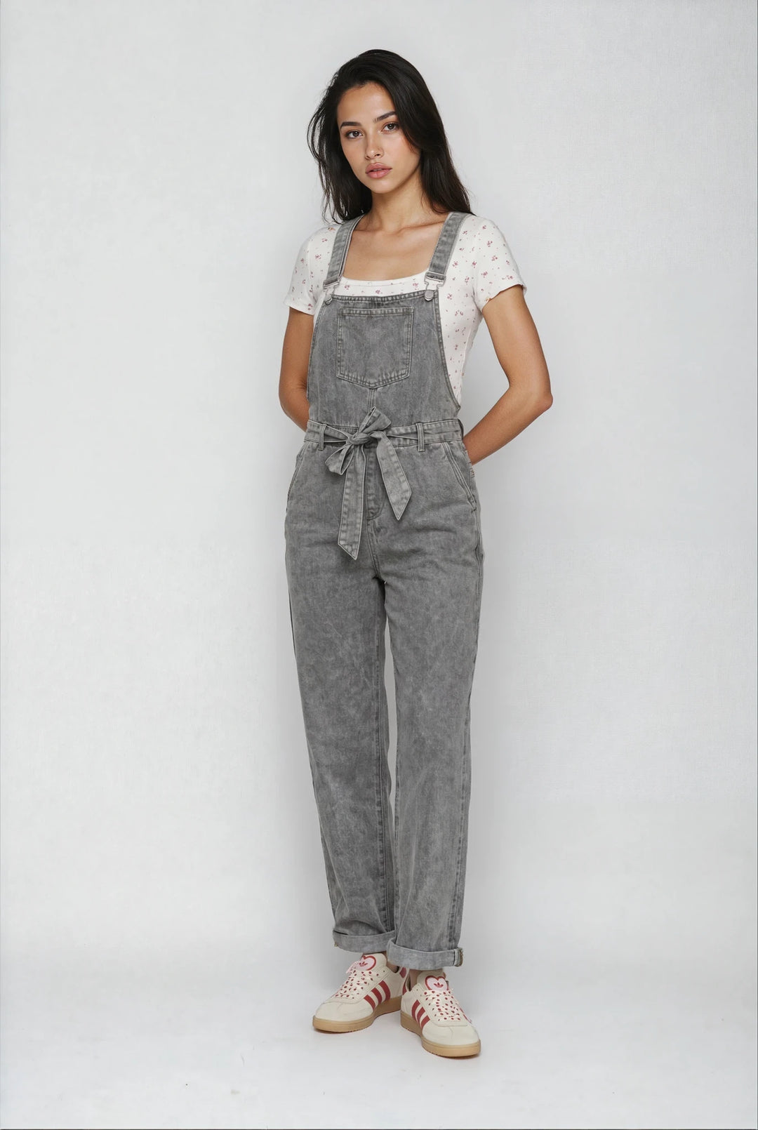 Woman wearing gray denim overalls on a white background
