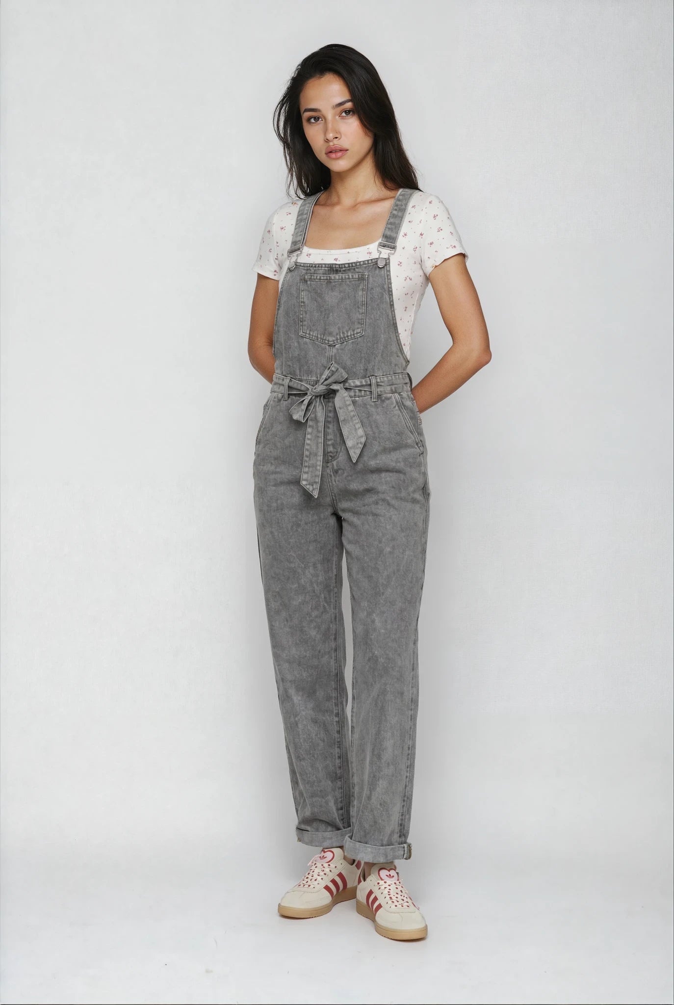 Woman wearing gray denim overalls on a white background