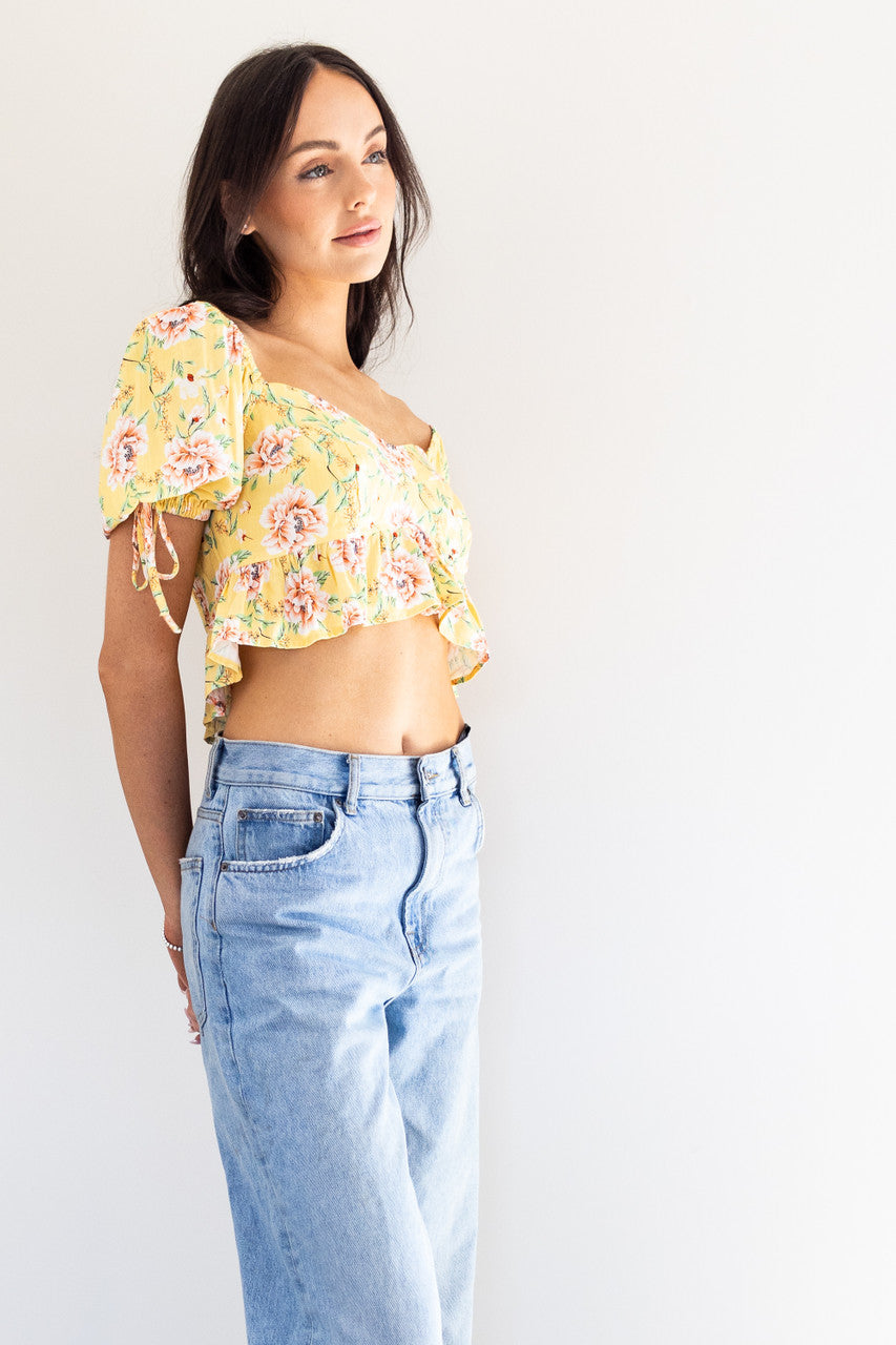 This cropped top boasts a flirty and feminine design with a flattering sweetheart neckline. The ties and puff sleeves add a playful touch, and it comes in both a versatile black colour and a bold yellow floral print. Perfect for dressing up or down, this top is a must-have addition to your summer wardrobe.


